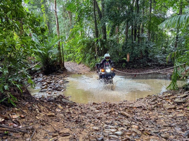 Motorcycle splashing through a puddle on a dirt trail
